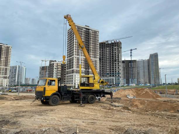 Large yellow mobility modern industrial construction crane mounted on a truck is used in the construction of new housing, houses, buildings in a big city Large yellow mobility modern industrial construction crane mounted on a truck is used in the construction of new housing, houses, buildings in a big city. crane boom stock pictures, royalty-free photos & images